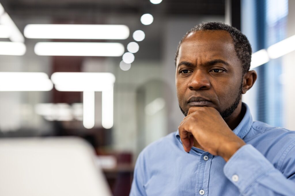 Focused African American office worker deep in thought at workplace