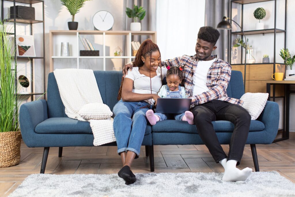 Happy african american family using laptop on couch