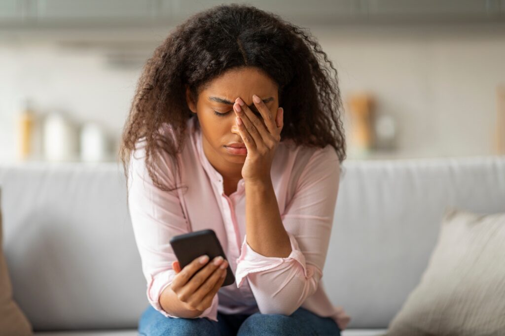 Worried black lady looking at phone screen